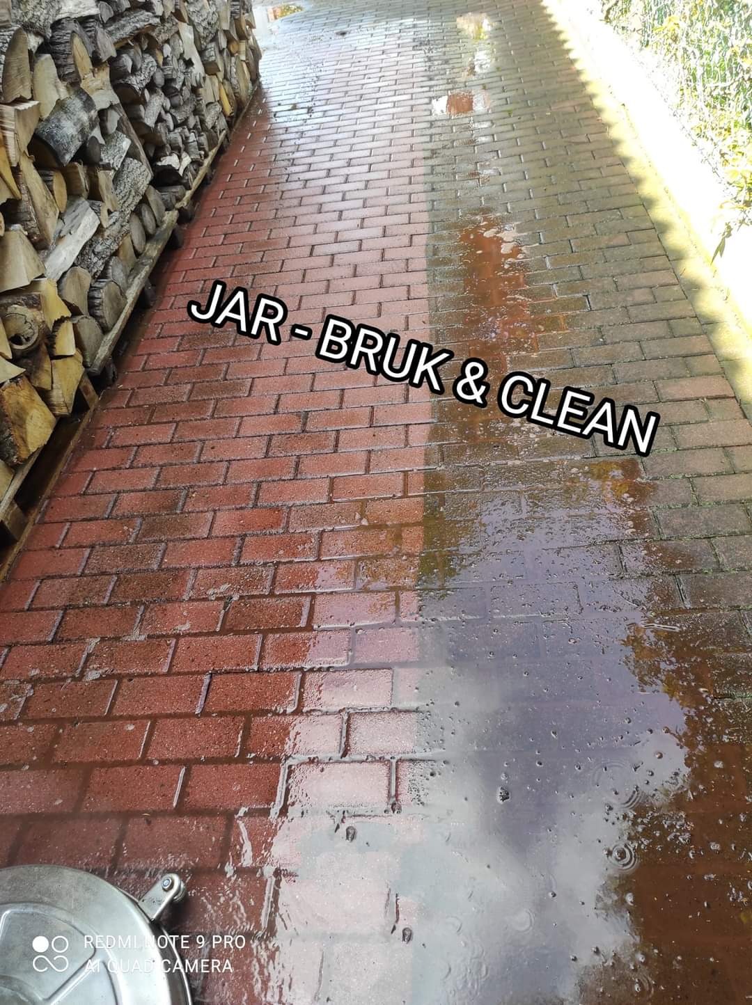 Częściowo umyta, mokra kostka brukowa z widocznym efektem czyszczenia, po lewej stronie sterta drewna, w dolnym rogu widoczny fragment urządzenia czyszczącego.