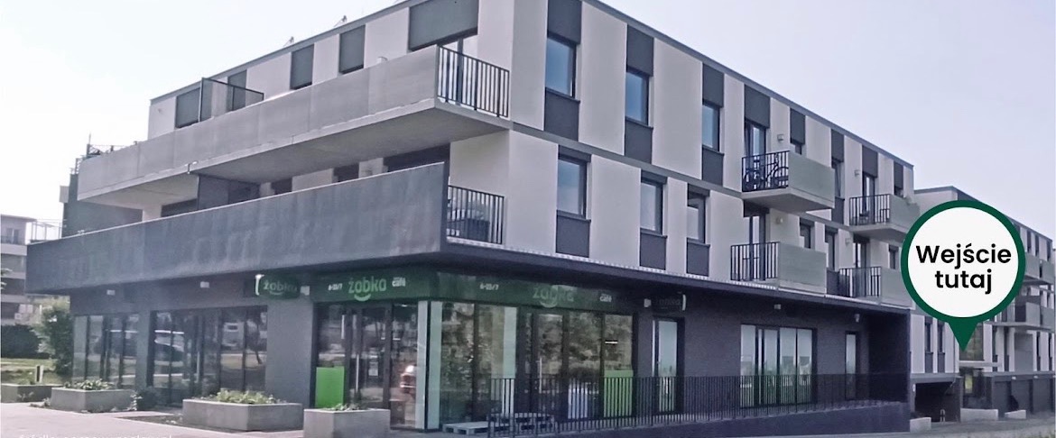Nowoczesny budynek mieszkalny z lokalem usługowym Żabka na parterze, widok z poziomu ulicy w słoneczny dzień.