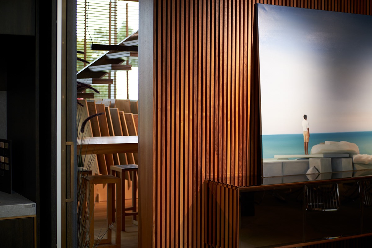 Wnętrze z drewnianą ścianą z listew, widoczne schody i obraz z motywem morskim, oświetlenie górne.