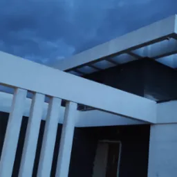 Surowy stan nowoczesnego domu z płaskim dachem i elementami dekoracyjnymi w postaci pionowych belek, sfotografowany o zmierzchu pod pochmurnym niebem.