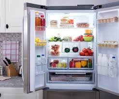 Wnętrze otwartej, nowoczesnej lodówki side-by-side z równomiernym oświetleniem LED, wypełnionej różnorodnymi produktami spożywczymi, m.in. owocami, warzywami, napojami i ciastami. Na półkach...