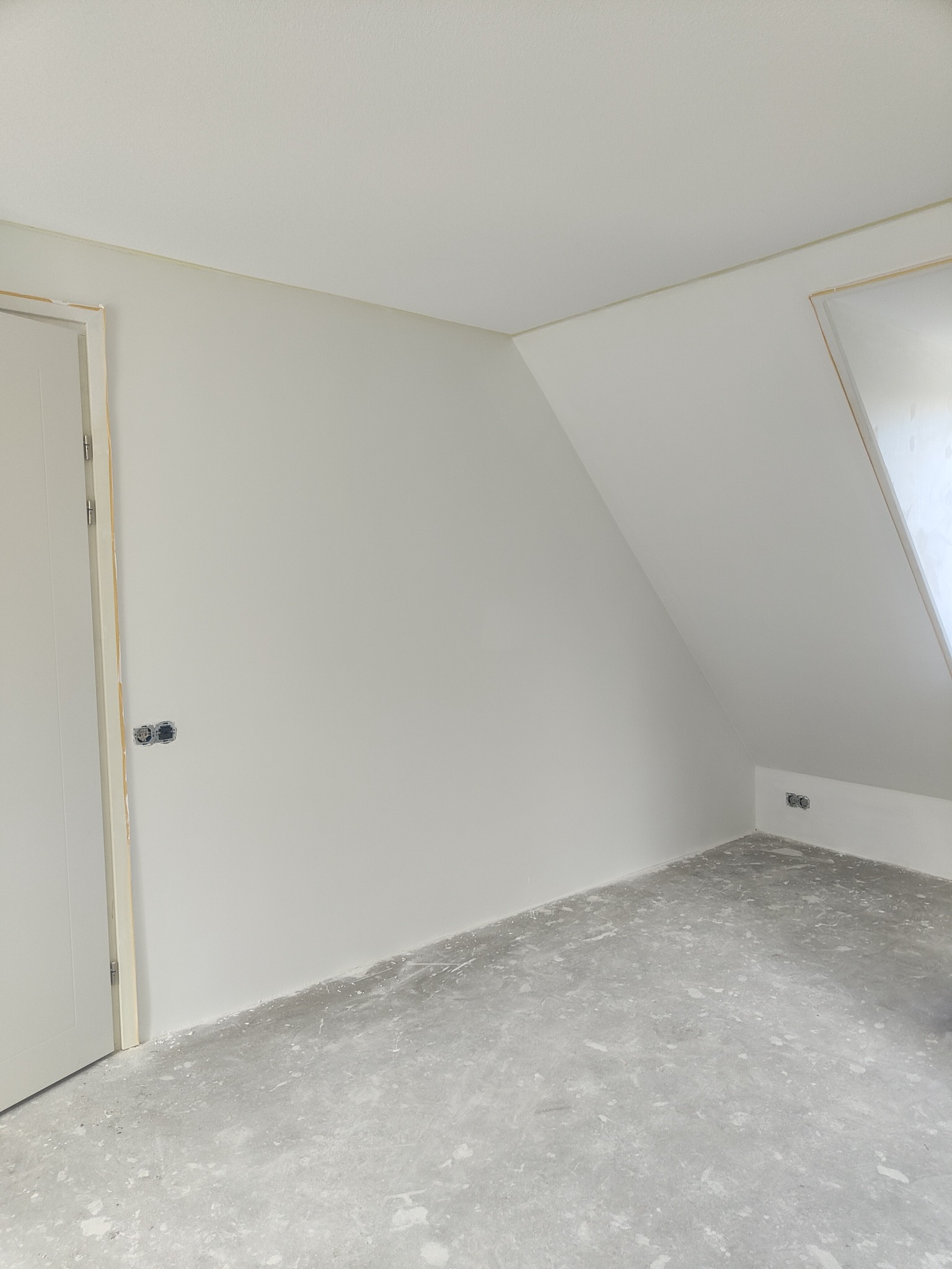Poddasze po szpachlowaniu i malowaniu na biało, widoczne puszki elektryczne i surowa podłoga w plamach po farbie.