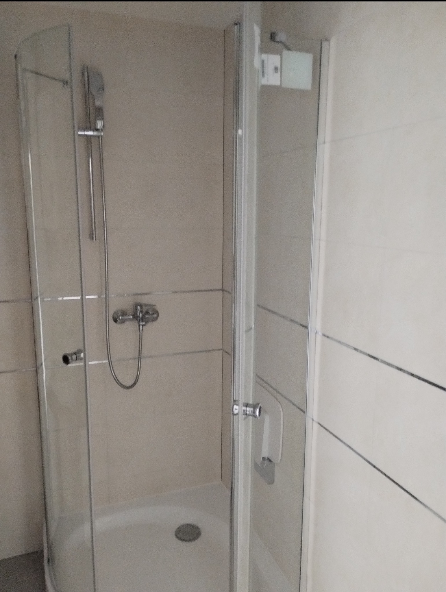 Kabina prysznicowa z chromowaną armaturą i beżowymi płytkami z dekoracyjnymi listwami