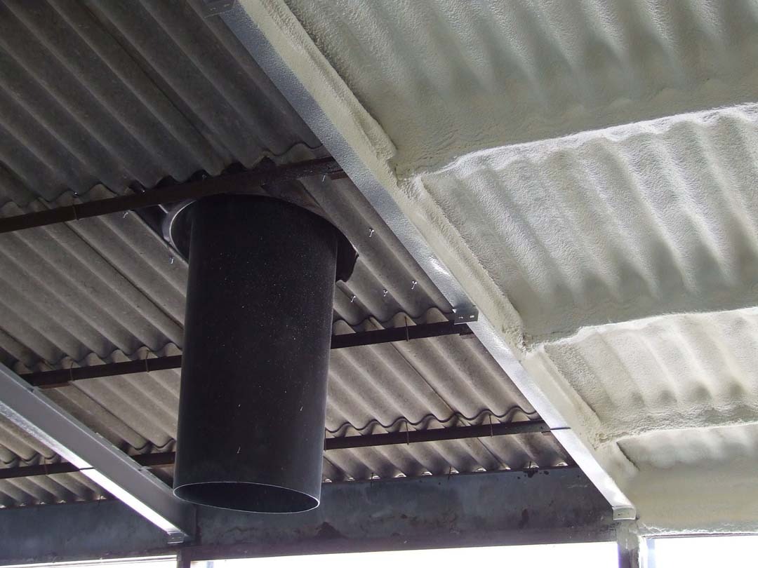 Poddasze z blachy falistej częściowo pokryte sztywną pianą izolacyjną, widoczny czarny przewód wentylacyjny.