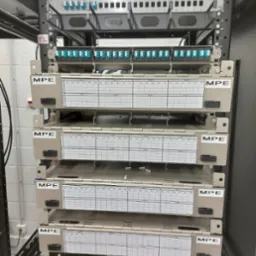 Panel krosowniczy światłowodowy MPE w szafie rack, zainstalowany w serwerowni w Poznaniu. Widoczne porty światłowodowe i oznaczenia kabli.