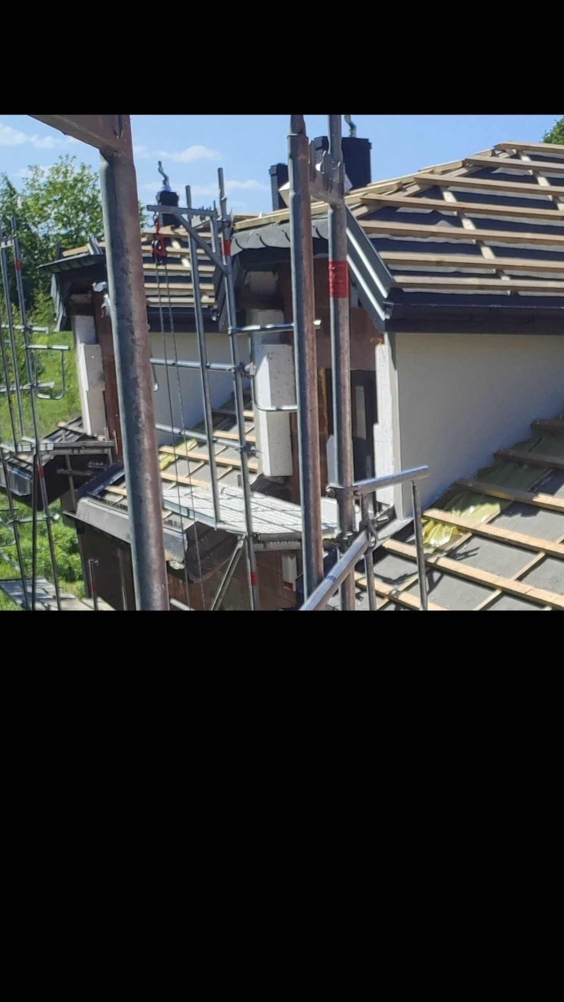 Ocieplanie elewacji budynku jednorodzinnego z użyciem rusztowania; widoczne styropianowe płyty i wełna mineralna.