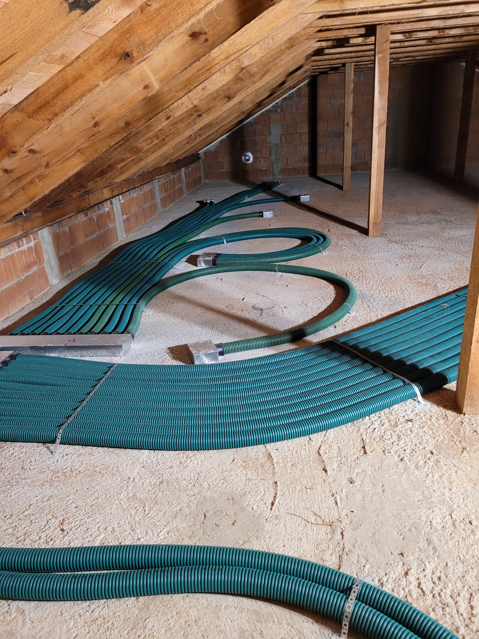 Zielone, karbowane rury wentylacyjne ułożone w surowym poddaszu w Złoczewie, prawdopodobnie w trakcie instalacji systemu rekuperacji.