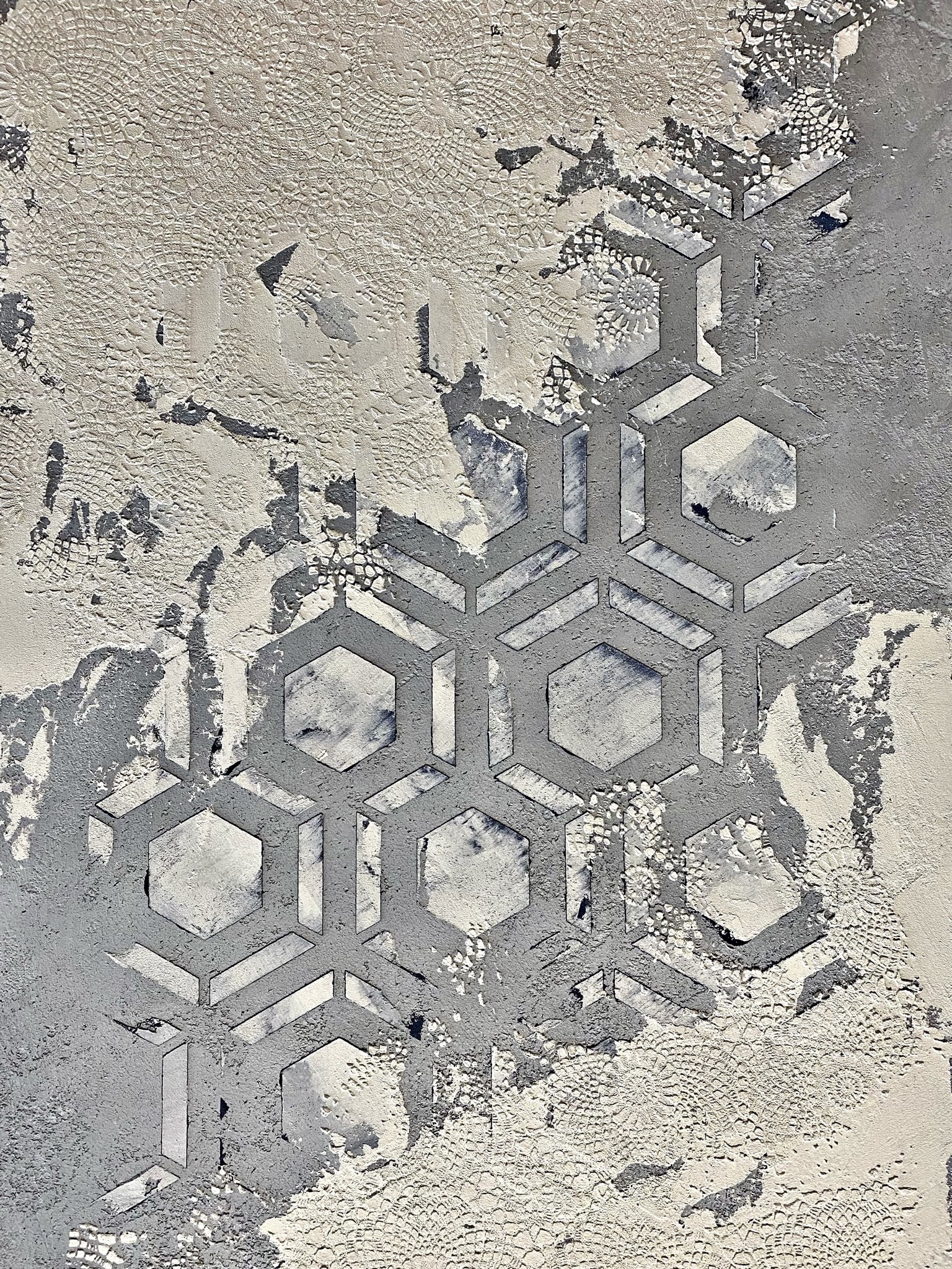 Posadzka żywiczna z efektem dekoracyjnym: fragment powierzchni z odciskiem koronki i nakładającym się wzorem geometrycznym z sześciokątów, w odcieniach szarości i bieli.