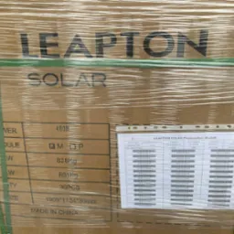 Paleta z modułami fotowoltaicznymi Leapton Solar, owinięta folią i zabezpieczona zielonymi taśmami. Widoczna etykieta z informacjami technicznymi modułów.