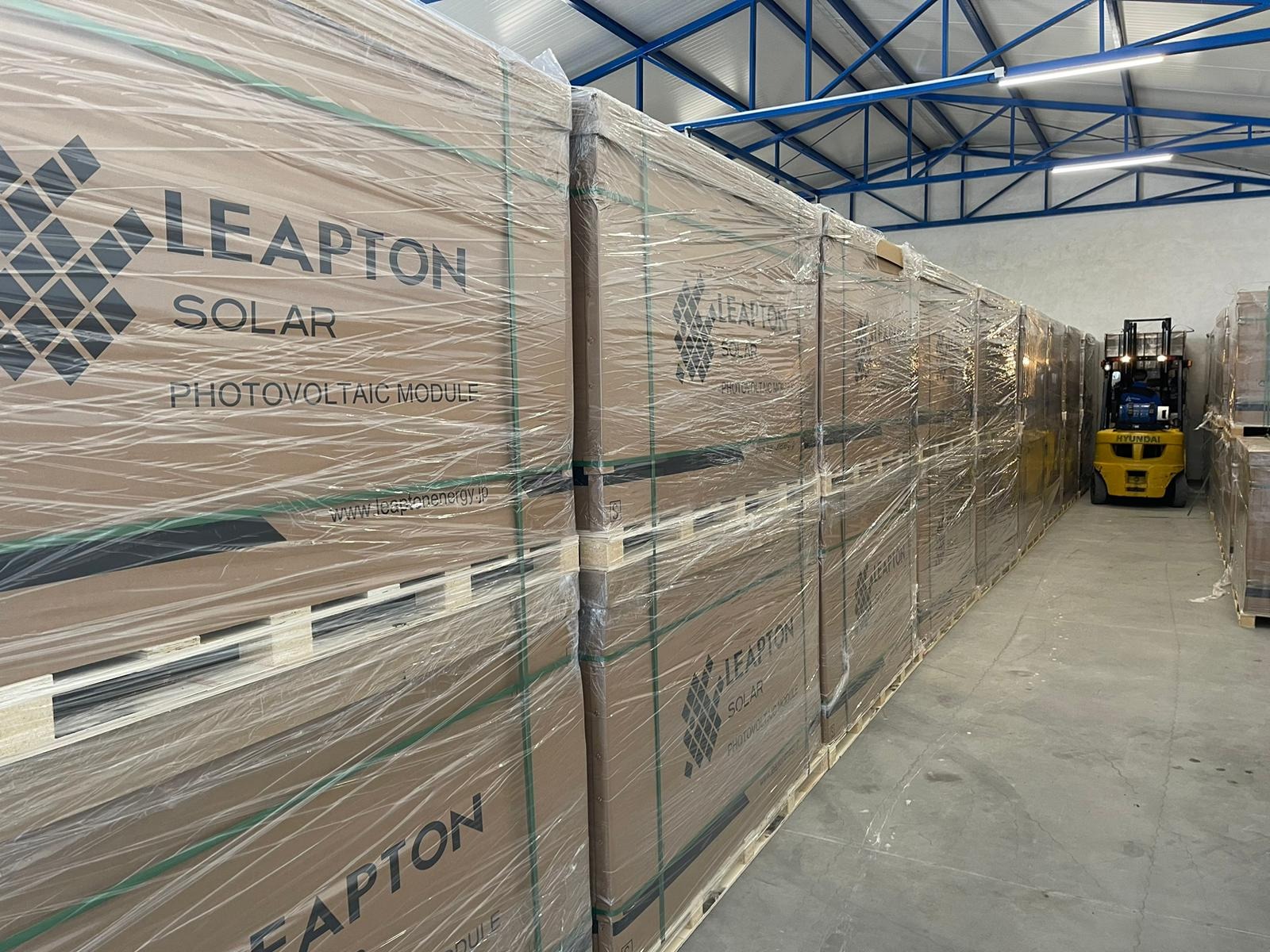 Magazyn z paletami zapakowanych modułów słonecznych Leapton Solar, w tle widoczny wózek widłowy Hyundai.