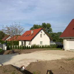 Przygotowanie podłoża z kruszywa pod przyszły podjazd w Ziębicach, widoczne obrzeża i rura kanalizacyjna.