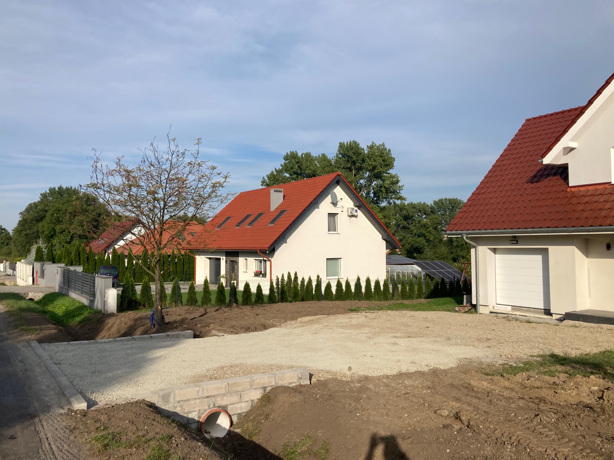 Przygotowanie podłoża z kruszywa pod przyszły podjazd w Ziębicach, widoczne obrzeża i rura kanalizacyjna.