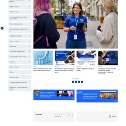 migomedia (od 2009) - Dwie kobiety w przestrzeni miejskiej, jedna w niebieskiej koszulce z logo IOM, trzyma tablet, druga z różowymi włosami słucha, prawdopodobnie rozmawiają o sprawach związanych z migracją.