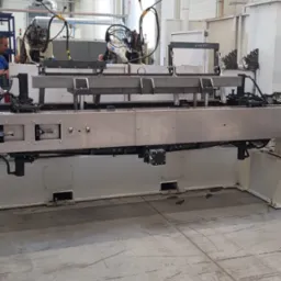 Automatyczna linia spawalnicza w hali produkcyjnej, widoczne roboty spawalnicze i elementy konstrukcji stalowej, suwnica podwieszana.