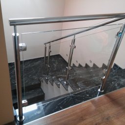 Balustrady Maciejewski - Szklana balustrada ze stalowymi słupkami na schodach z ciemnego marmuru, widok z góry.