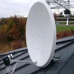 Antena satelitarna i antena naziemna zamontowane na grafitowym dachu blaszanym, widok na jesienny krajobraz.