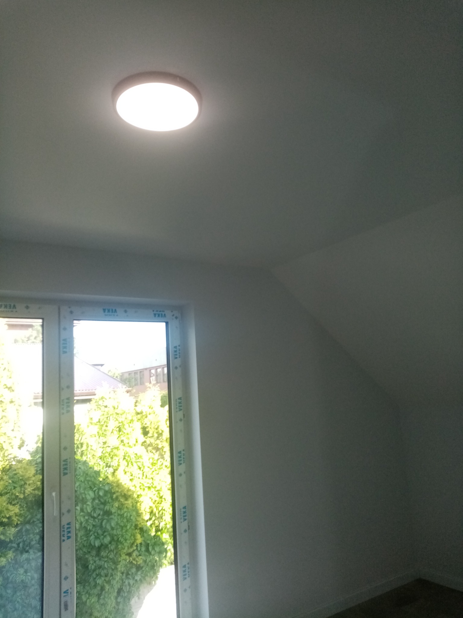 Wnętrze poddasza po remoncie z oknem PCV i zamontowaną okrągłą lampą sufitową LED.