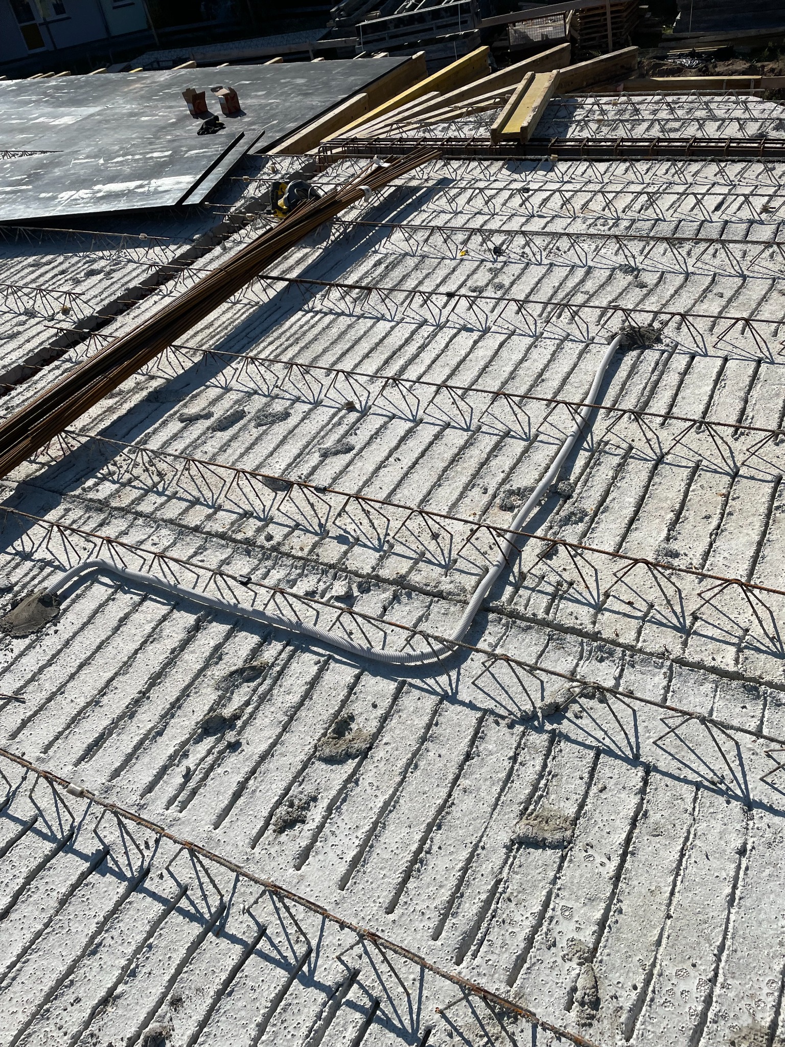 Montaż instalacji elektrycznej w stropie w Trzcińsko-Zdrój: widok na betonowy strop z ułożonymi przewodami elektrycznymi w peszlu i elementami konstrukcji zbrojeniowej przed zalaniem betonem.