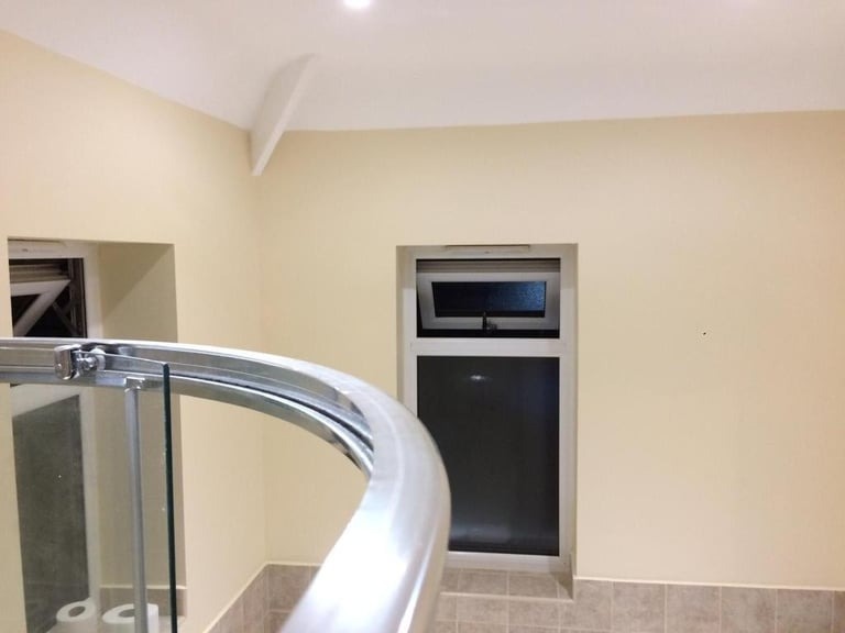 Jasne wnętrze z beżowymi ścianami po odświeżeniu, widoczny fragment kabiny prysznicowej z chromowanymi elementami i dwa okna z otwartymi lufcikami.