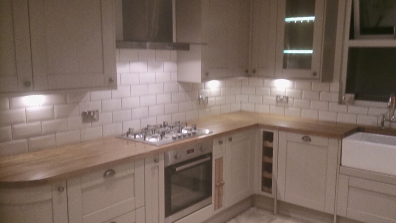 Jasna kuchnia w stylu retro z białymi płytkami metra na ścianie, drewnianym blatem i zabudową meblową z frezowanymi frontami.