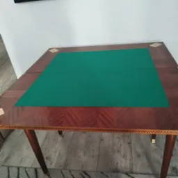 Rozkładany st&oacute;ł do gry z zielonym suknem, wykończony drewnem o wzorze jodełki i inkrustacjami.