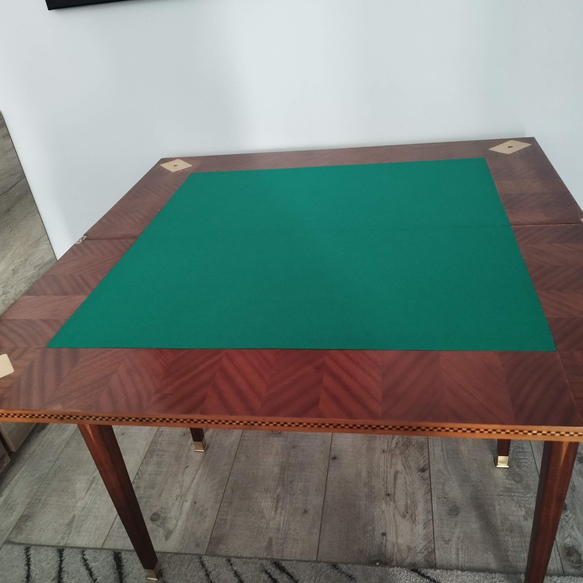 Rozkładany stół do gry z zielonym suknem, wykończony drewnem o wzorze jodełki i inkrustacjami.