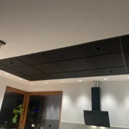Czarny, kasetonowy sufit podwieszany z oświetleniem punktowym w nowoczesnej kuchni, widok z dołu, z fragmentem okna i okapu kuchennego.