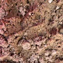 Bliskie ujęcie czerwono-brązowego kruszywa z widocznymi ziarnami różnej wielkości i pojedynczymi jasnymi kamykami.