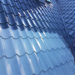 MW Team - Częściowo umyty, ciemnoszary dach z blachodachówki modułowej, z widocznym kominem dachowym i liną zabezpieczającą.