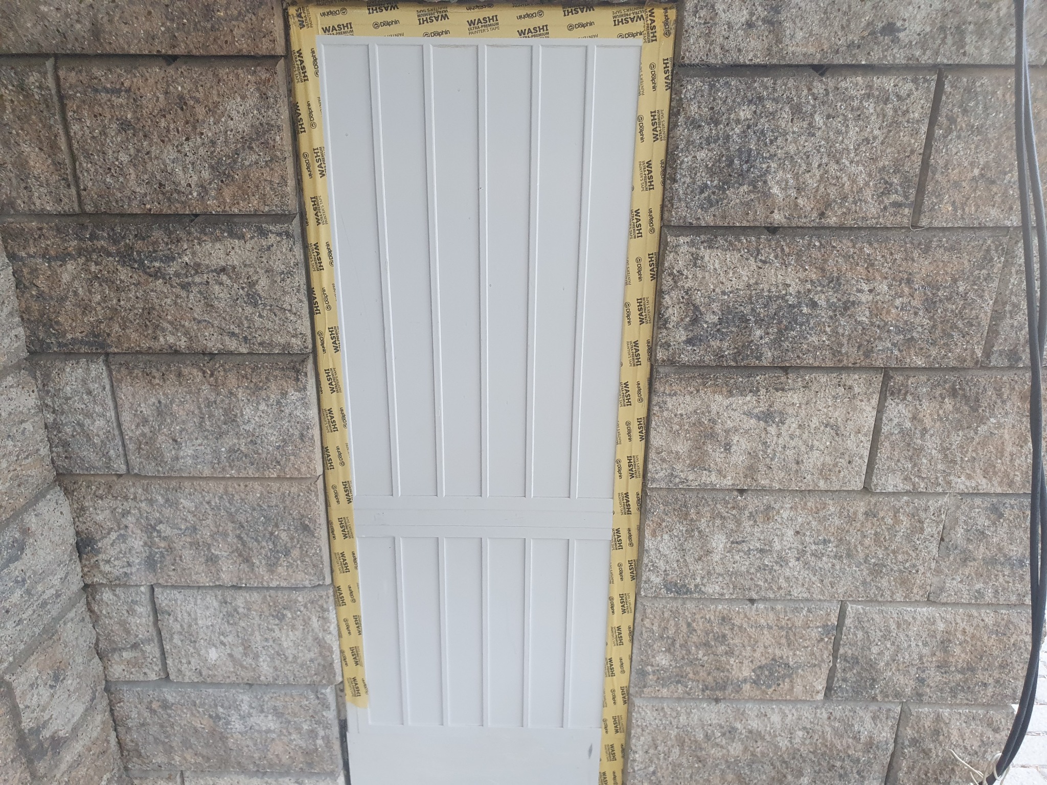 Białe panele dachowe zabezpieczone taśmą malarską przed montażem w obramowaniu z kamiennych bloków.