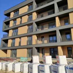 Stanislav Timonov - Nowoczesny blok mieszkalny w trakcie ocieplania elewacji, widoczne opakowania wełny mineralnej SOPREMA na pierwszym planie.