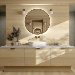 Architekt Natalia Orawska - Jasna łazienka z drewnianymi panelami, okrągłym lustrem z podświetleniem LED, białą umywalką nablatową i dekoracyjnymi trawami w szklanych wazonach.