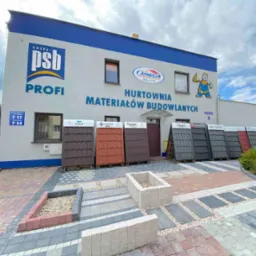 Ekspozycja materiałów budowlanych przed hurtownią: różnorodne modele dachówek i aranżacje nawierzchni z kostki brukowej, prezentowane na zewnątrz budynku z logo PSB Profi i Omega Bezak.