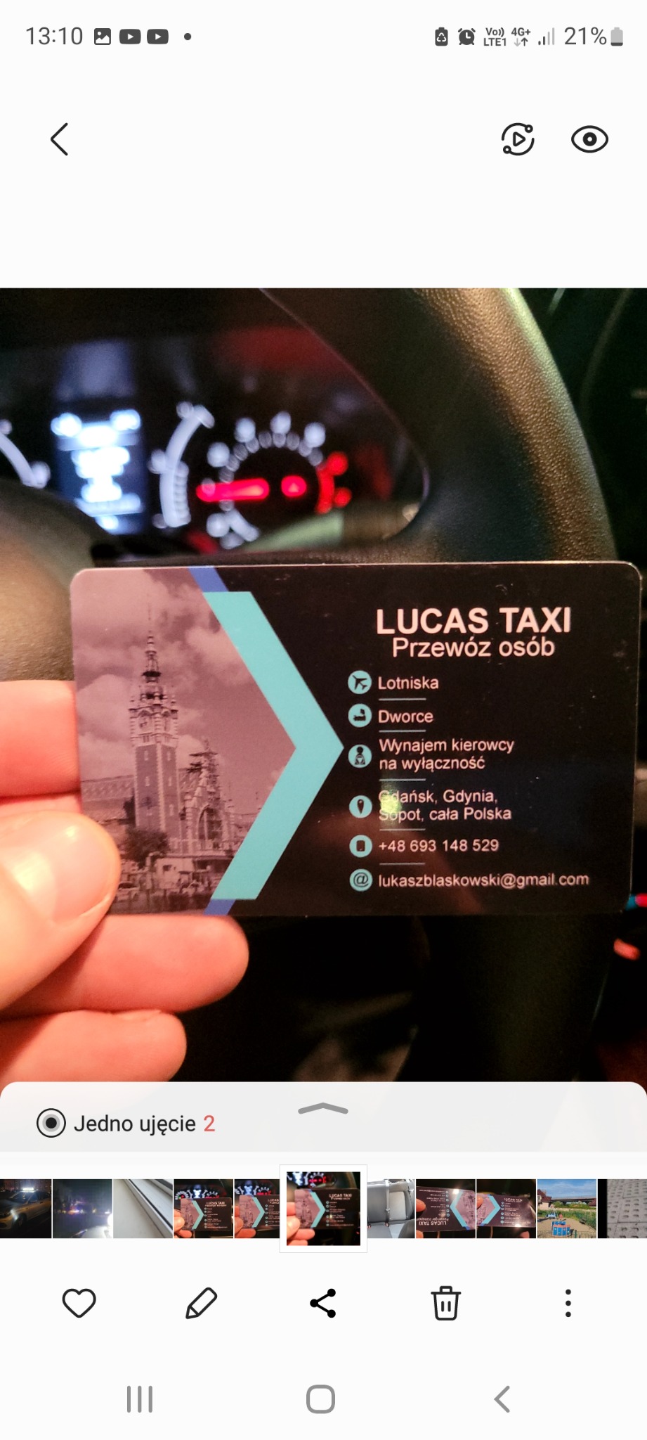 Wnętrze samochodu, na pierwszym planie wizytówka firmy Lucas Taxi z adresem email i numerem telefonu, oferującej przewóz osób z lotnisk i dworców w Gdańsku, Gdyni i Sopocie.