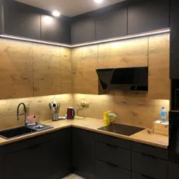 Nowoczesna kuchnia z czarnymi szafkami dolnymi i drewnopodobnymi górnymi, podświetlona listwami LED, z czarnym zlewem i płytą indukcyjną.