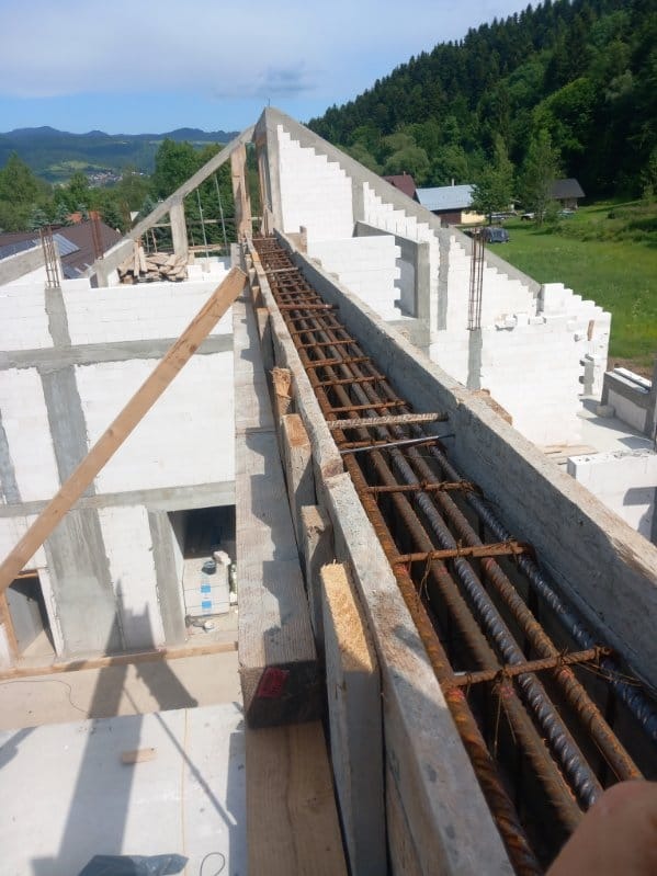 Budowa domu z betonu komórkowego w Lubomierzu: widok na zbrojenie stropu w szalunku, z tłem górskim i fragmentami konstrukcji ścian.