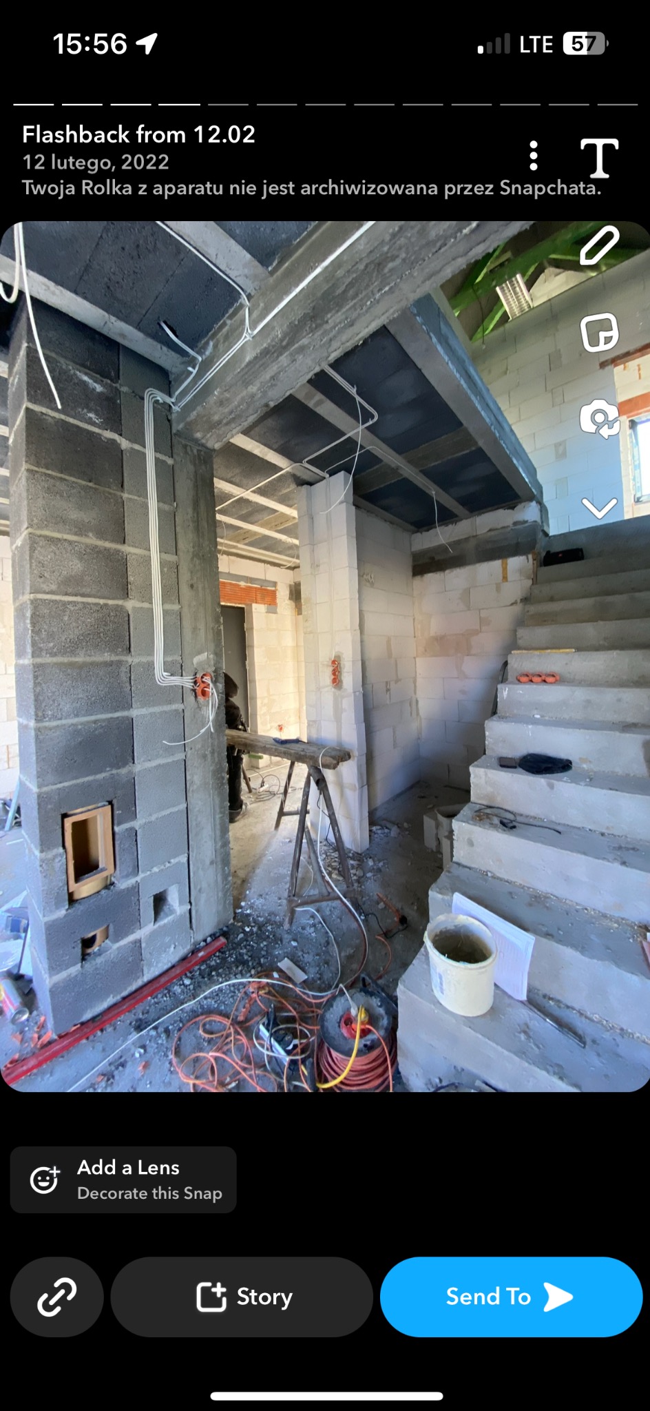 Wnętrze w trakcie murowania ścian z bloczków betonowych, widoczne instalacje elektryczne w peszlach, prowizoryczne schody betonowe i narzędzia pracy.