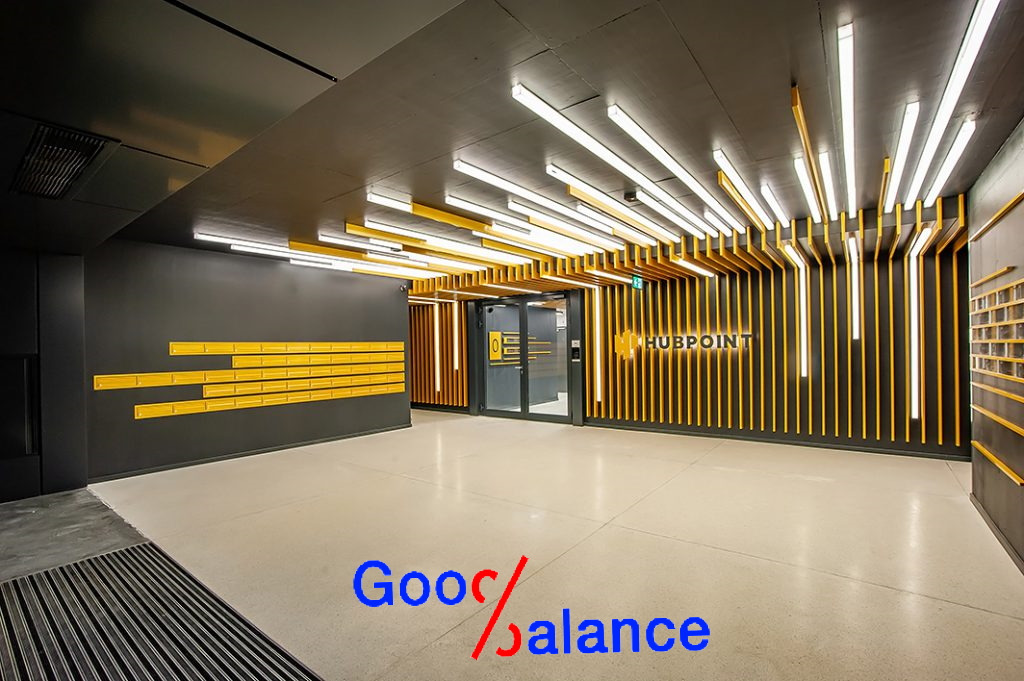 Nowoczesne wnętrze biurowe Hubpoint z elementami dekoracyjnymi w kolorze żółtym i oświetleniem LED, widoczne skrzynki pocztowe i logo firmy.