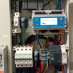 INSTAL3D Shevchenko Dmytro - Rozdzielnica elektryczna z zainstalowanymi modułami, zabezpieczeniami i sterownikami, widoczne okablowanie oraz elementy montażowe na szynie DIN.