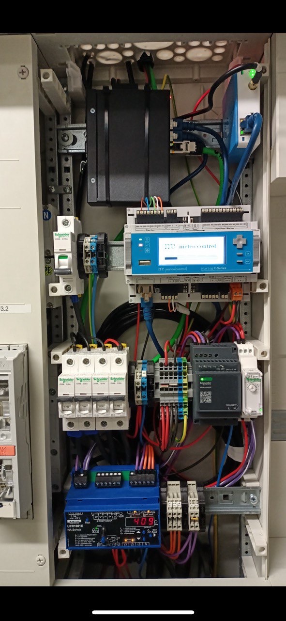 Rozdzielnica elektryczna z zainstalowanymi modułami, zabezpieczeniami i sterownikami, widoczne okablowanie oraz elementy montażowe na szynie DIN.