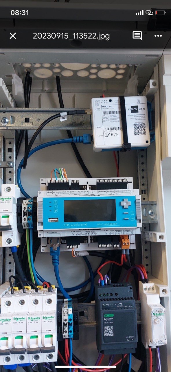 Rozdzielnia elektryczna z zamontowanymi zabezpieczeniami, sterownikiem logicznym z ekranem i modułem komunikacyjnym INSYS icom, widoczne przewody, bezpieczniki Schneider Electric i złącza.