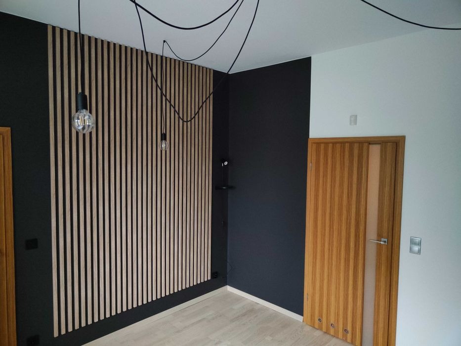 Nowoczesne wnętrze z drewnianą ścianą z lameli, czarną ścianą, drewnianymi drzwiami i wiszącymi żarówkami na kablach