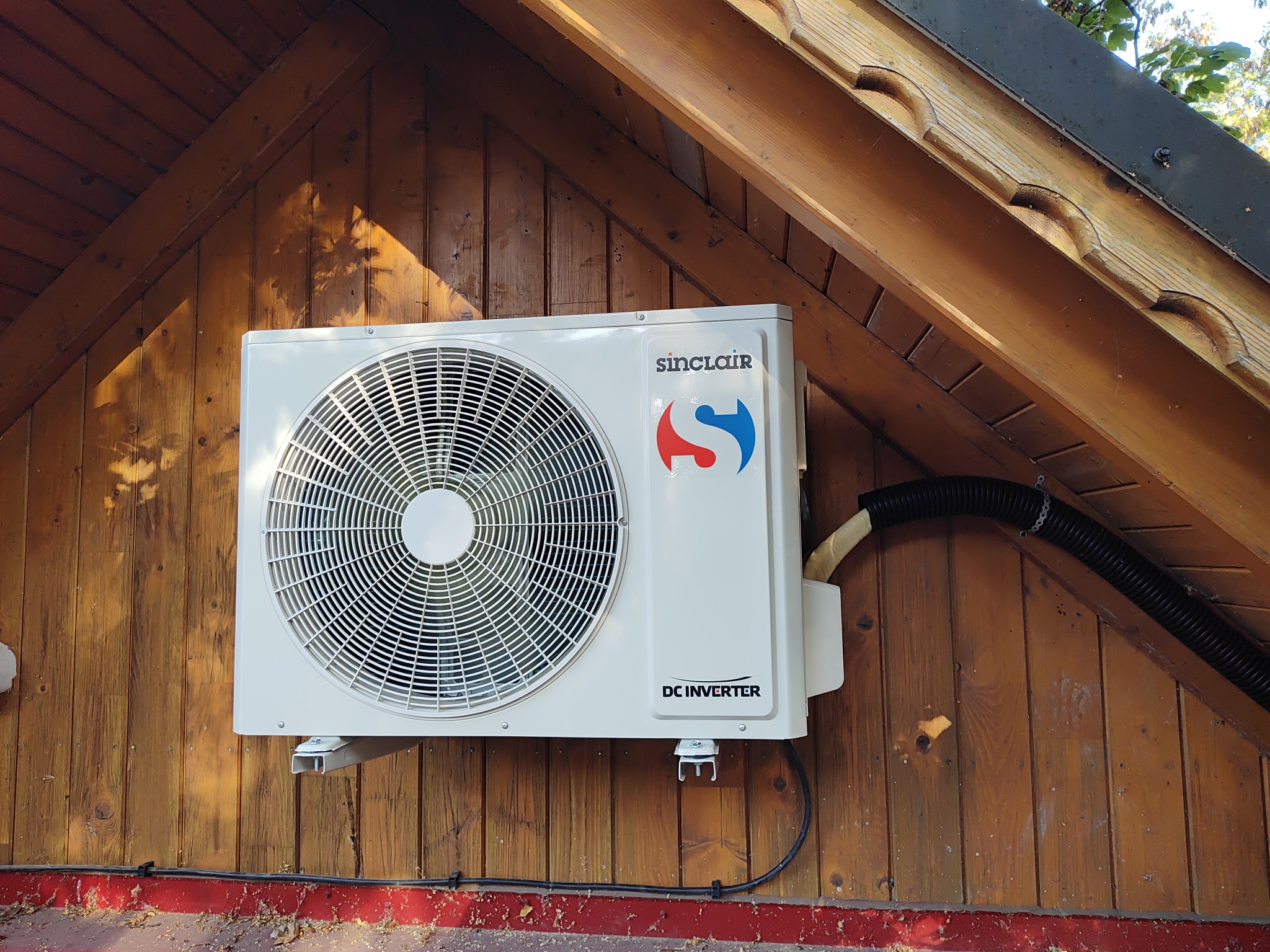 Zamontowana jednostka zewnętrzna klimatyzacji Sinclair na drewnianej elewacji budynku w Krakowie, widoczne przewody i elementy montażowe.