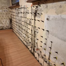 Zdjęcie prezentuje wypełnione otwory zaczynem cementowym z materiałem iniekcyjnym. Często przy spękanych ścianach, materiał iniekcyjny podawany ciśnieniowo, wypływa przez szczeliny lub przez otwarte pakery co świadczy o prawidłowym wypełnieniu ściany.