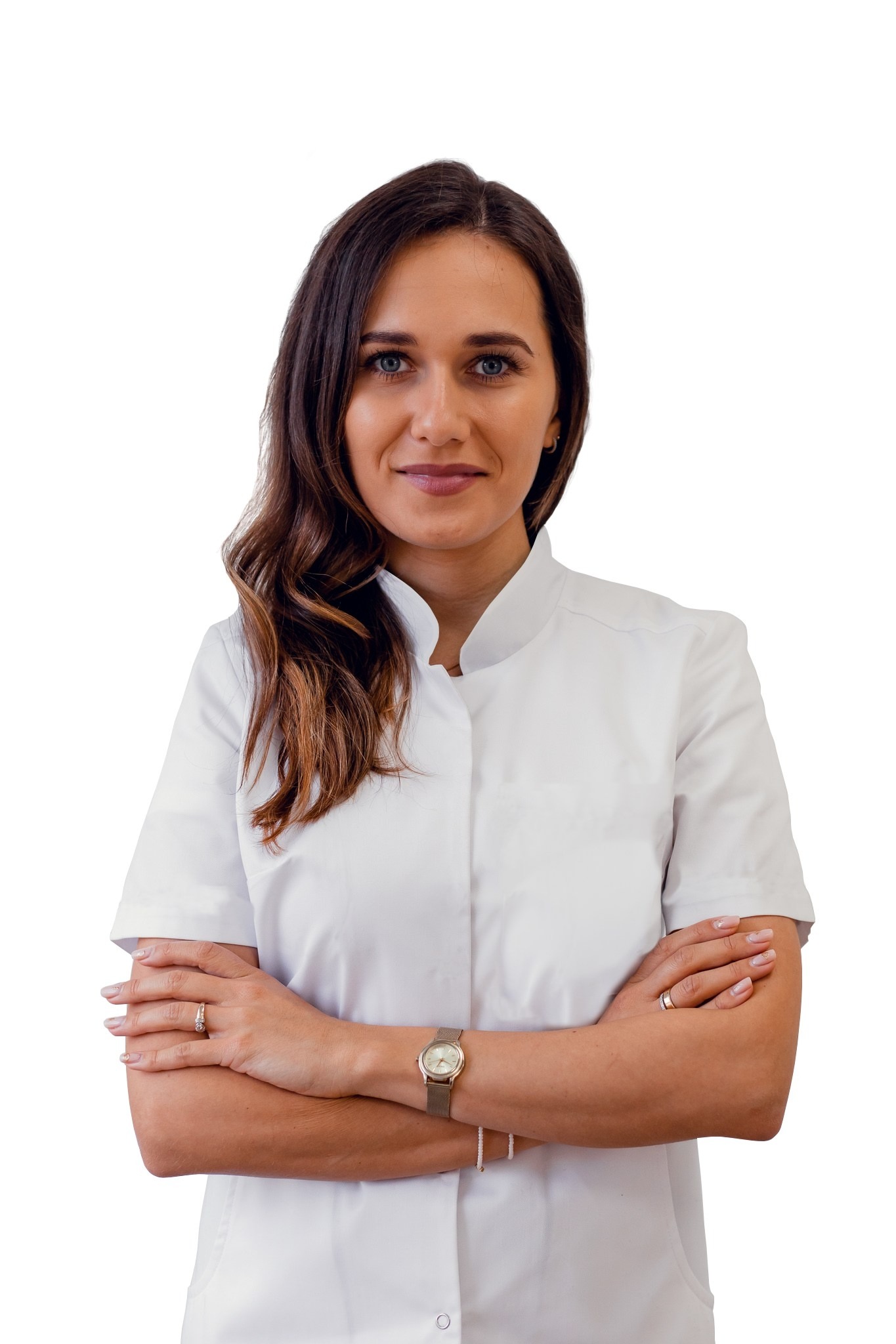 Portret uśmiechniętej kobiety w białym uniformie medycznym, ze skrzyżowanymi rękami, na białym tle.