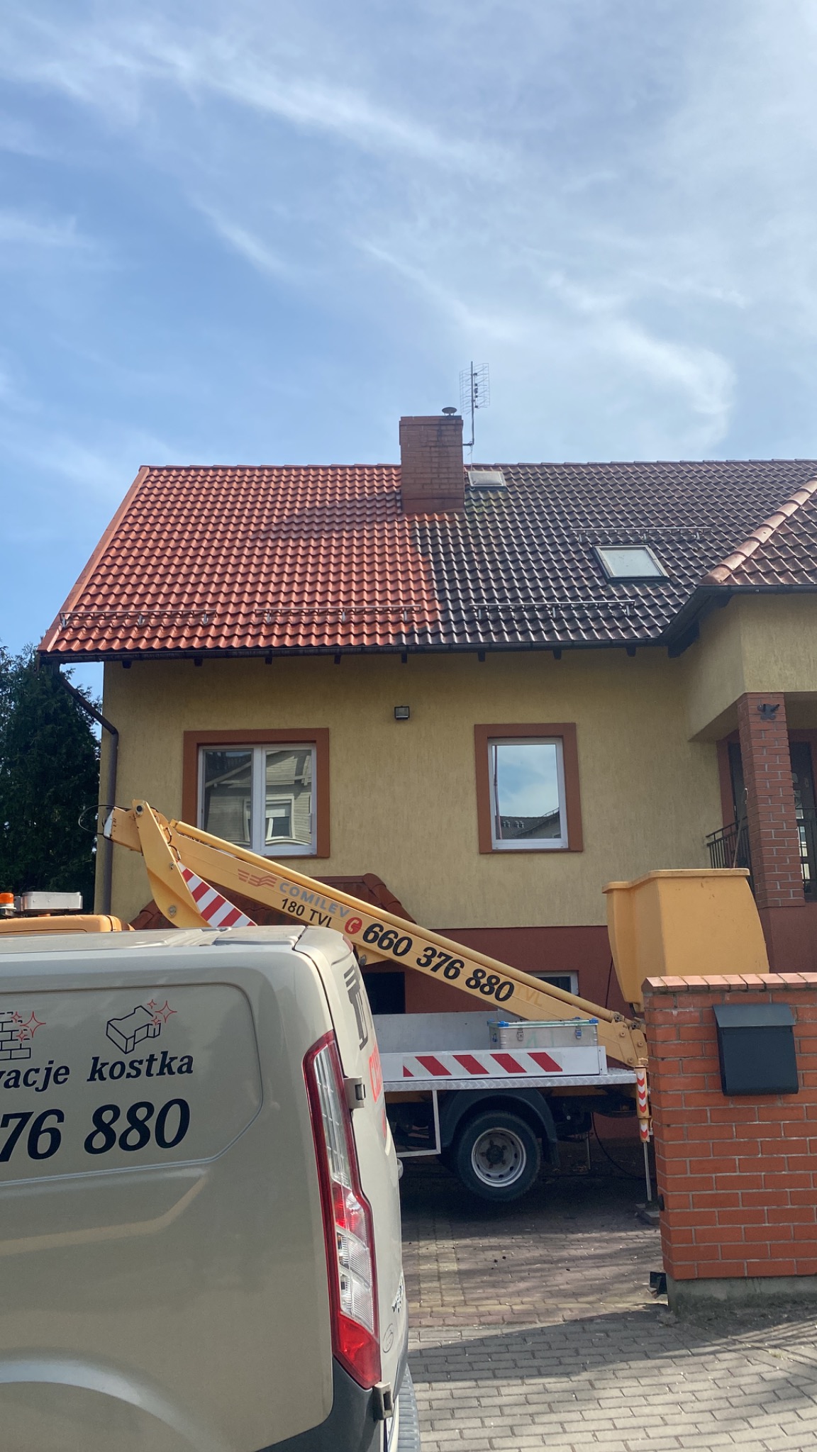 Częściowo wyczyszczony dach z czerwonej dachówki, widoczna różnica w kolorze, platforma podnośnika koszowego i częściowo widoczny samochód dostawczy z reklamą usług.