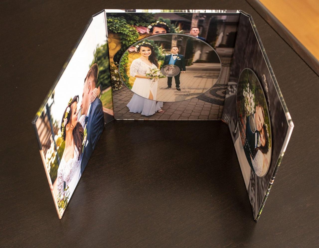 Rozkładany album z fotografiami ślubnymi i płytą DVD z nagraniem, prezentowany na ciemnym stole.
