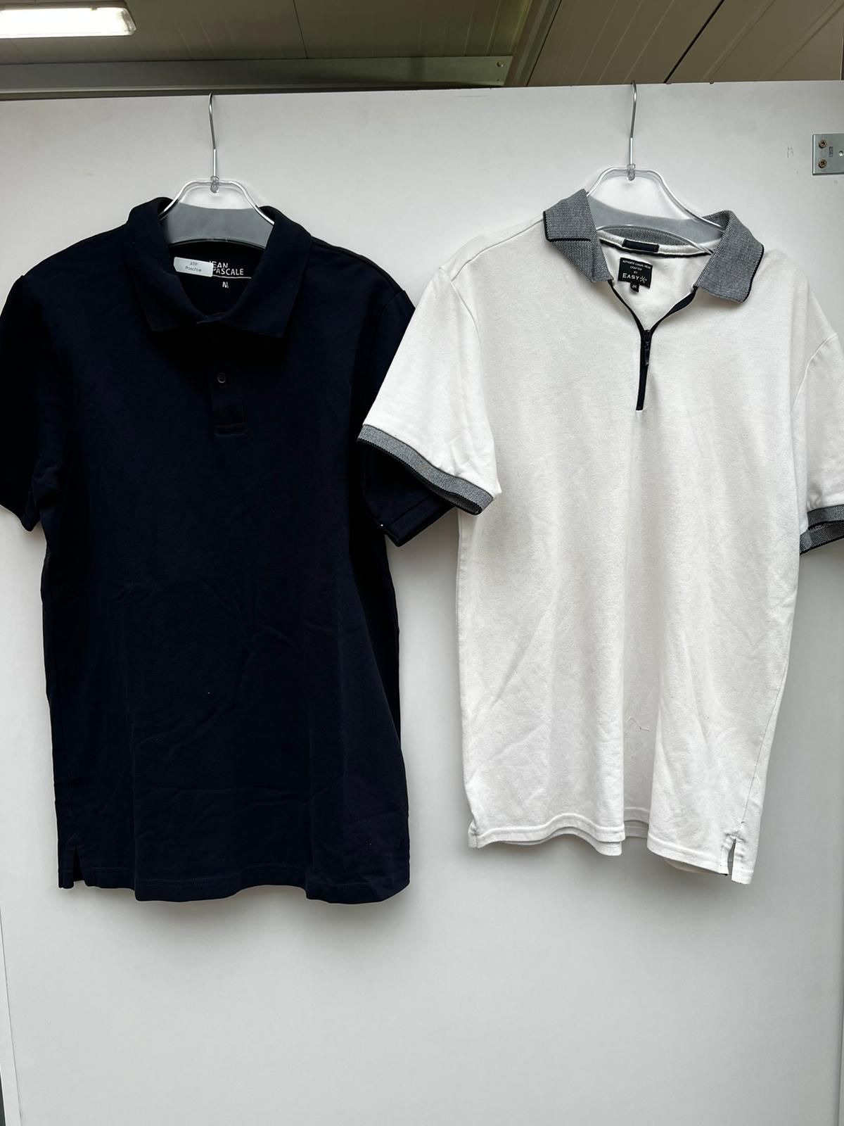 Dwie koszulki polo wiszące na wieszakach: granatowa z guzikami i biała z szarym kołnierzykiem zapinana na zamek błyskawiczny.