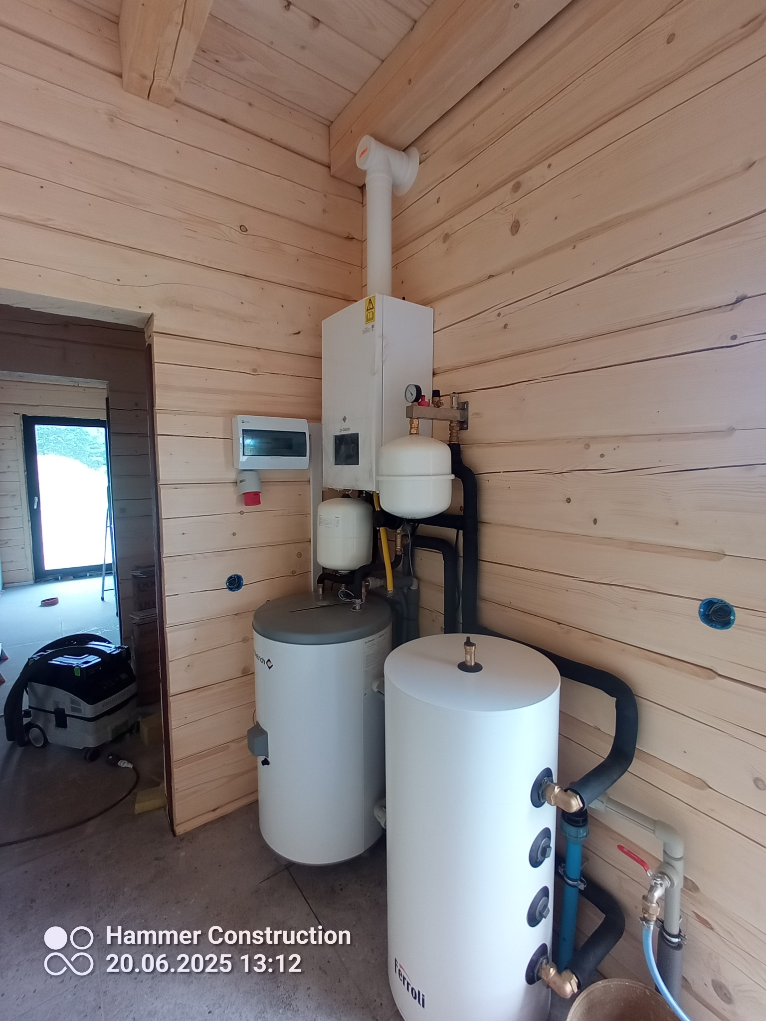 Nowoczesny piec gazowy Ferroli z zbiornikami w drewnianym domu. Instalacja grzewcza w trakcie montażu, widoczne rury i przewody. Dom w stylu skandynawskim.