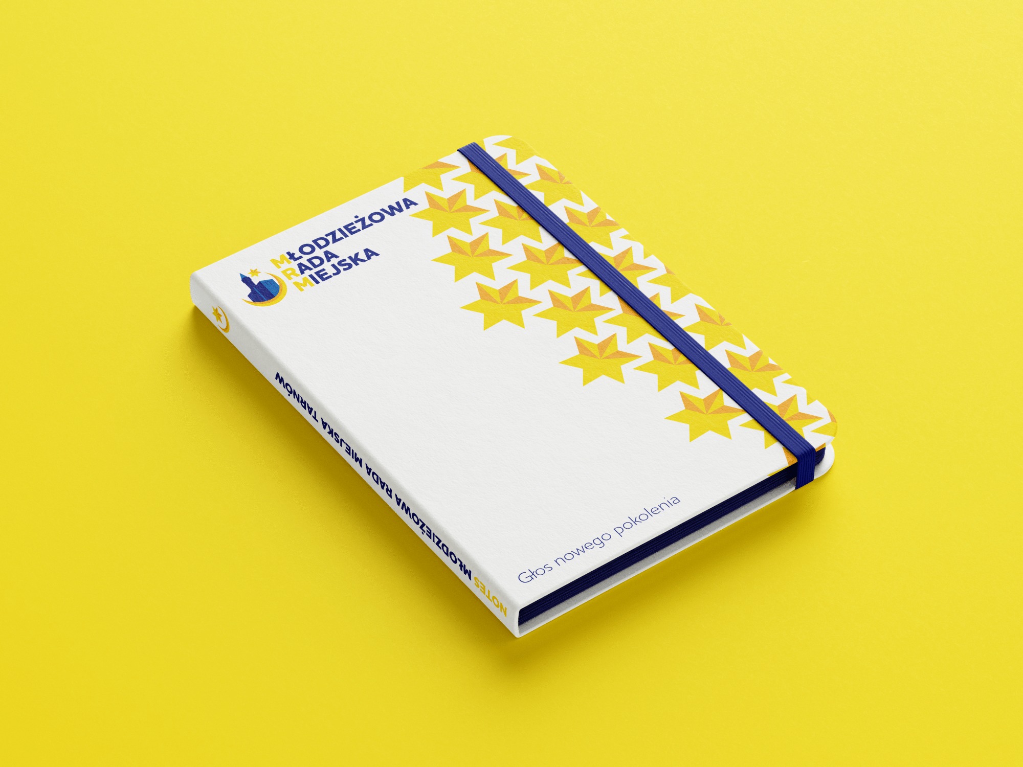 Notatnik z nadrukiem logo Młodzieżowej Rady Miejskiej Tarnowa, z motywem gwiazd i hasłem 'Głos nowego pokolenia', na żółtym tle.